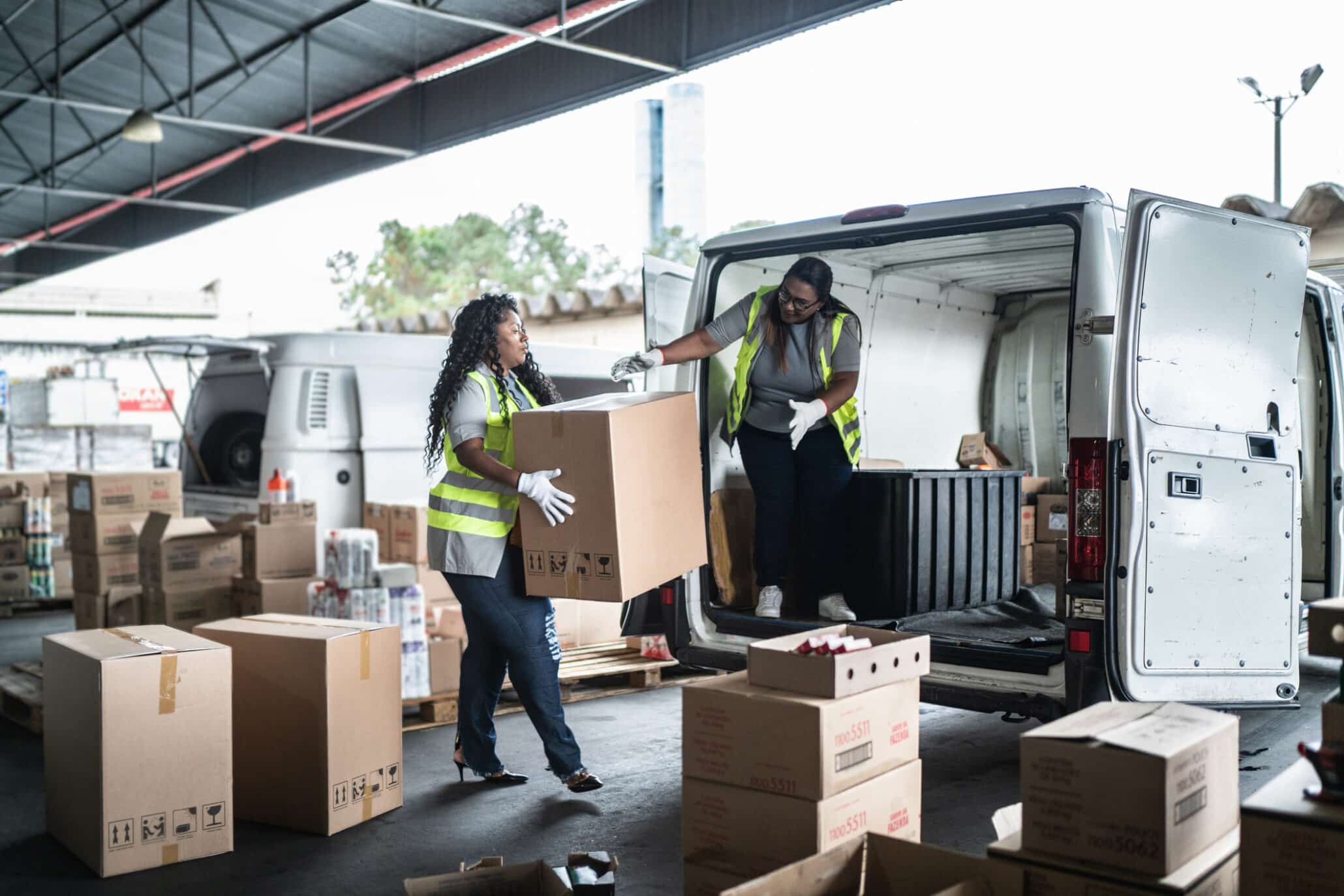 Zwei Frauen während ihres Zeitarbeiteinsatzes beim Packen von Paketen in einen Van