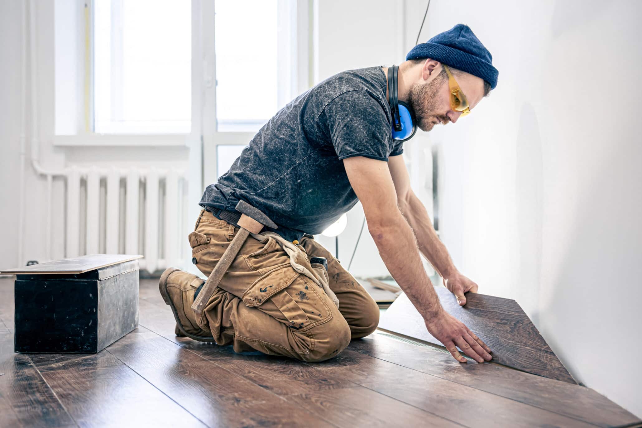 Mann der als Bodenleger arbeitet und gerade Laminat verlegt