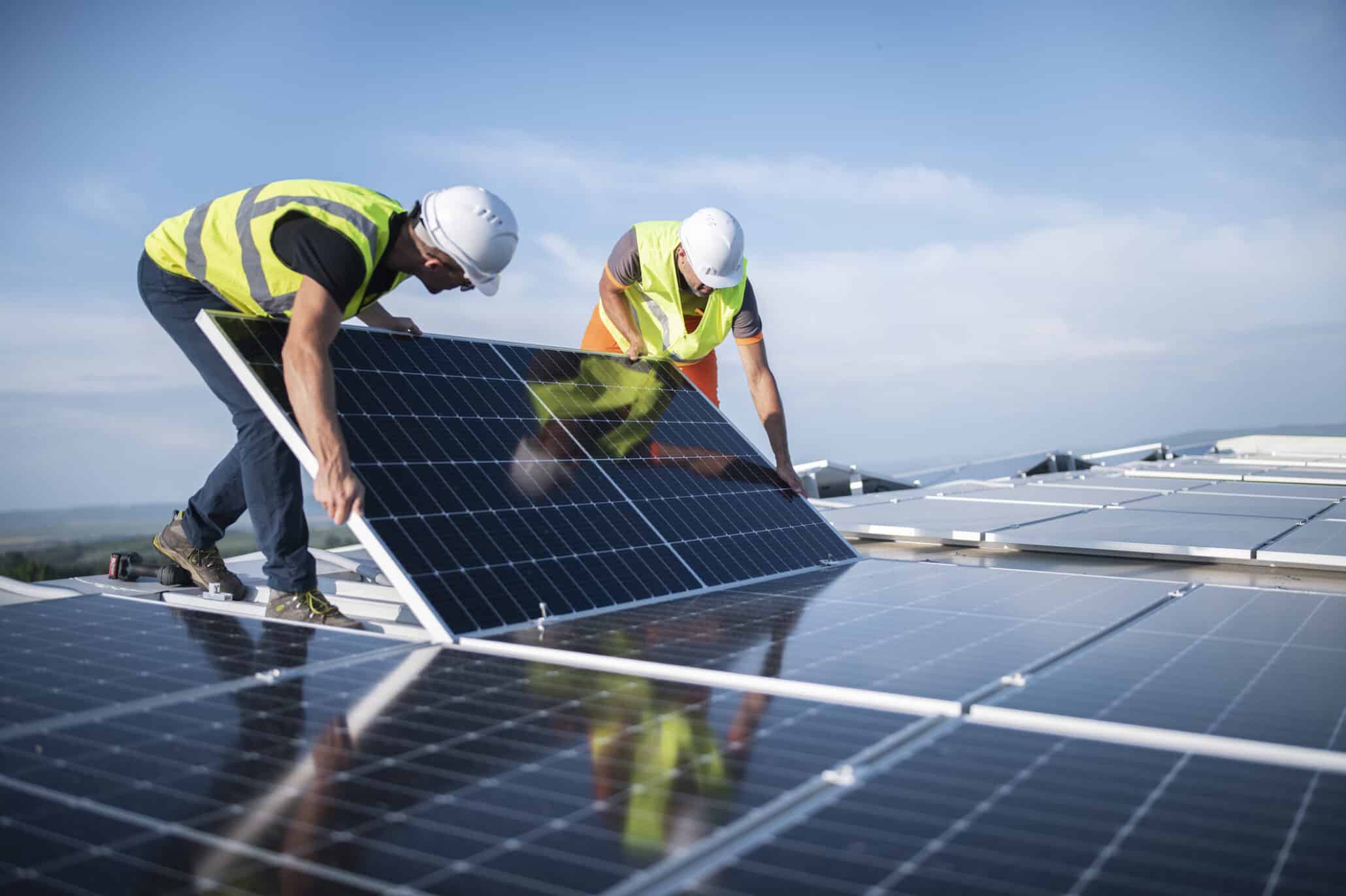 Zwei Elektriker beim Installieren eines Solar Panels auf einem Solardach.