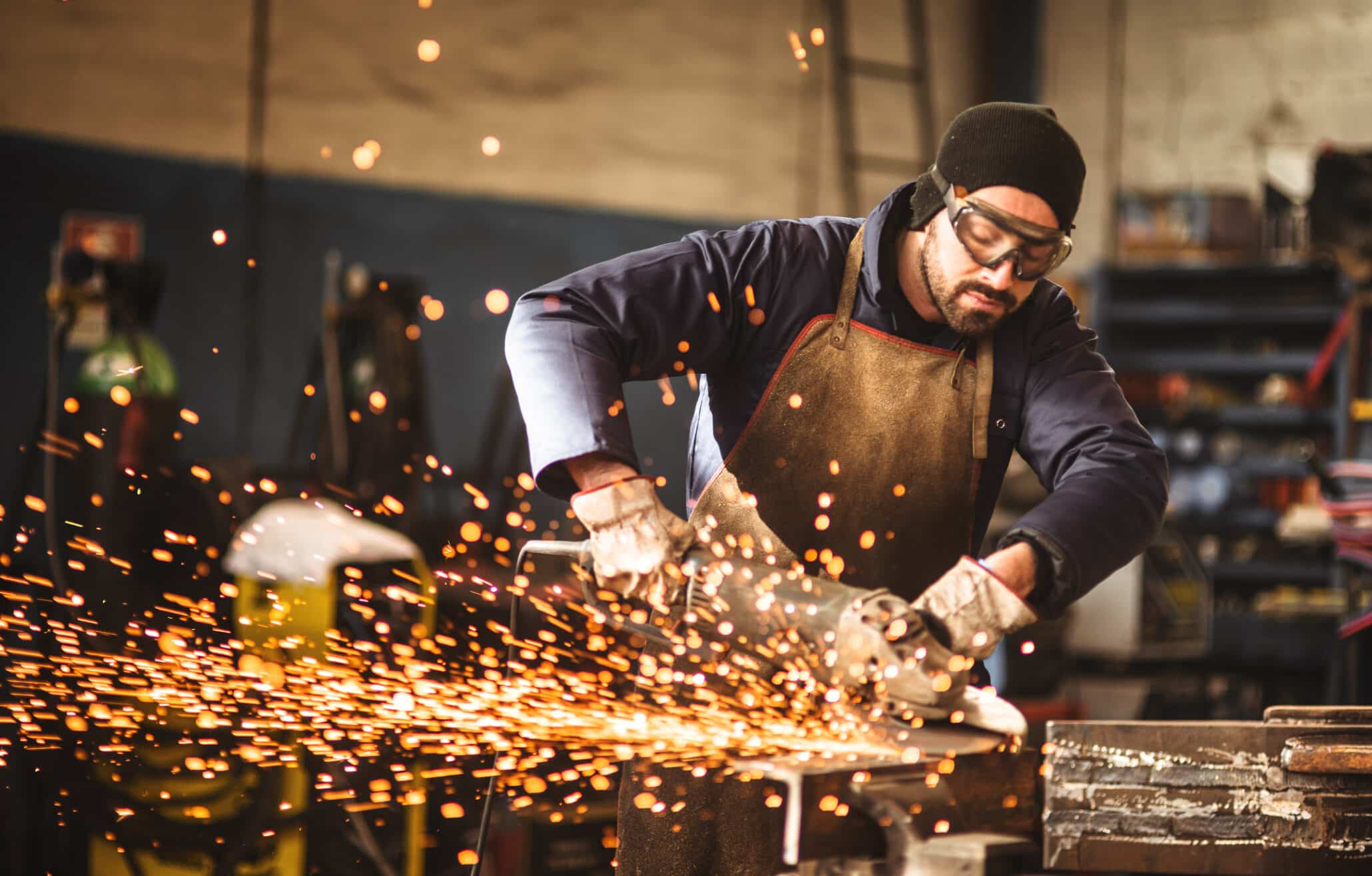 Schlosser in Schutzkleidung bei der Arbeit mit sprühenden Funken