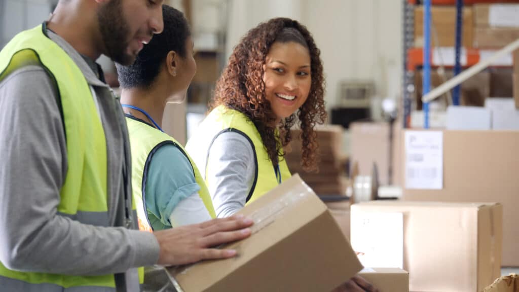 Drei Zeitarbeitnehmer beim Pakete verpacken in einem Lagerhaus