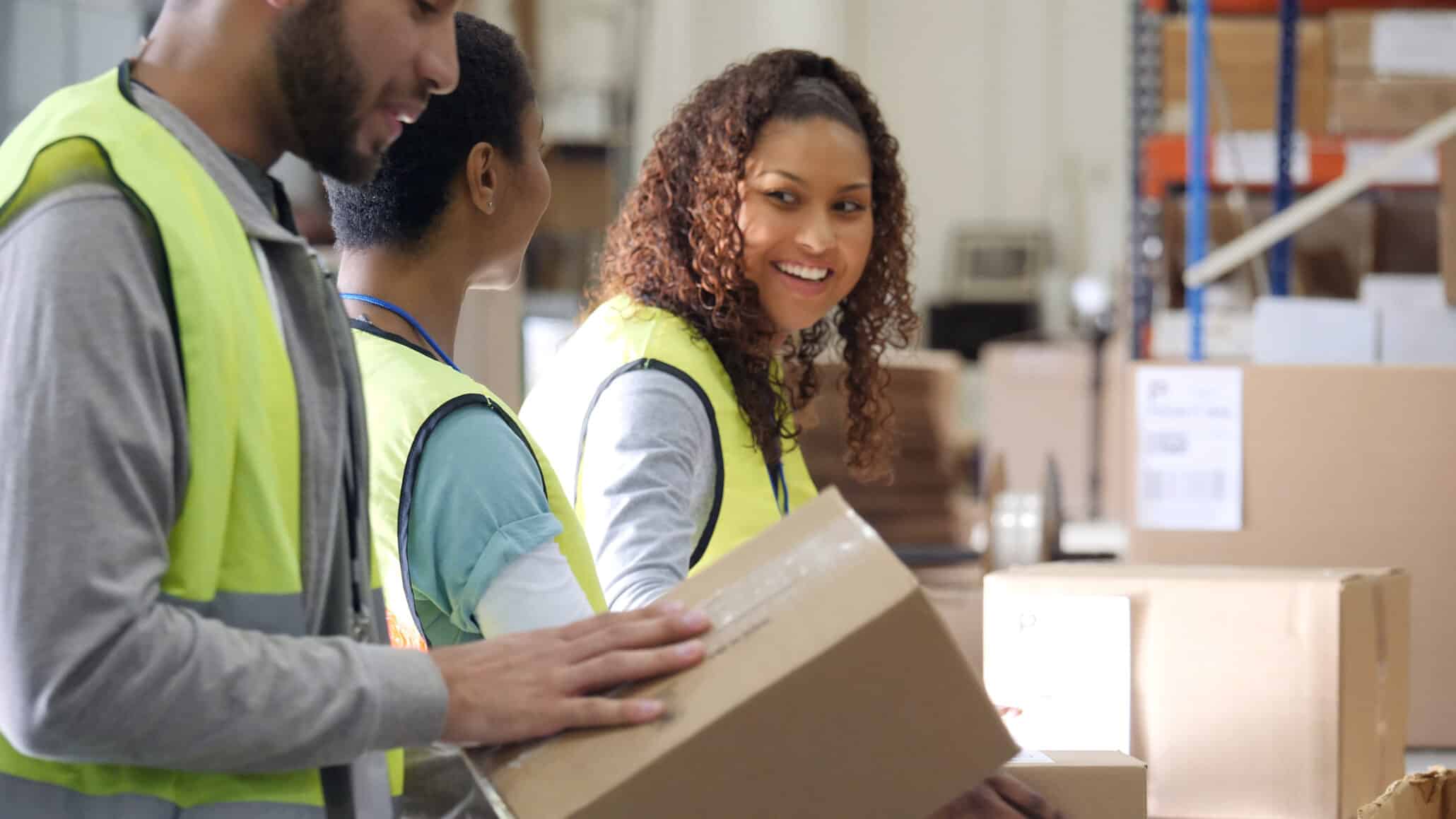 Drei Zeitarbeitnehmer beim Pakete verpacken in einem Lagerhaus