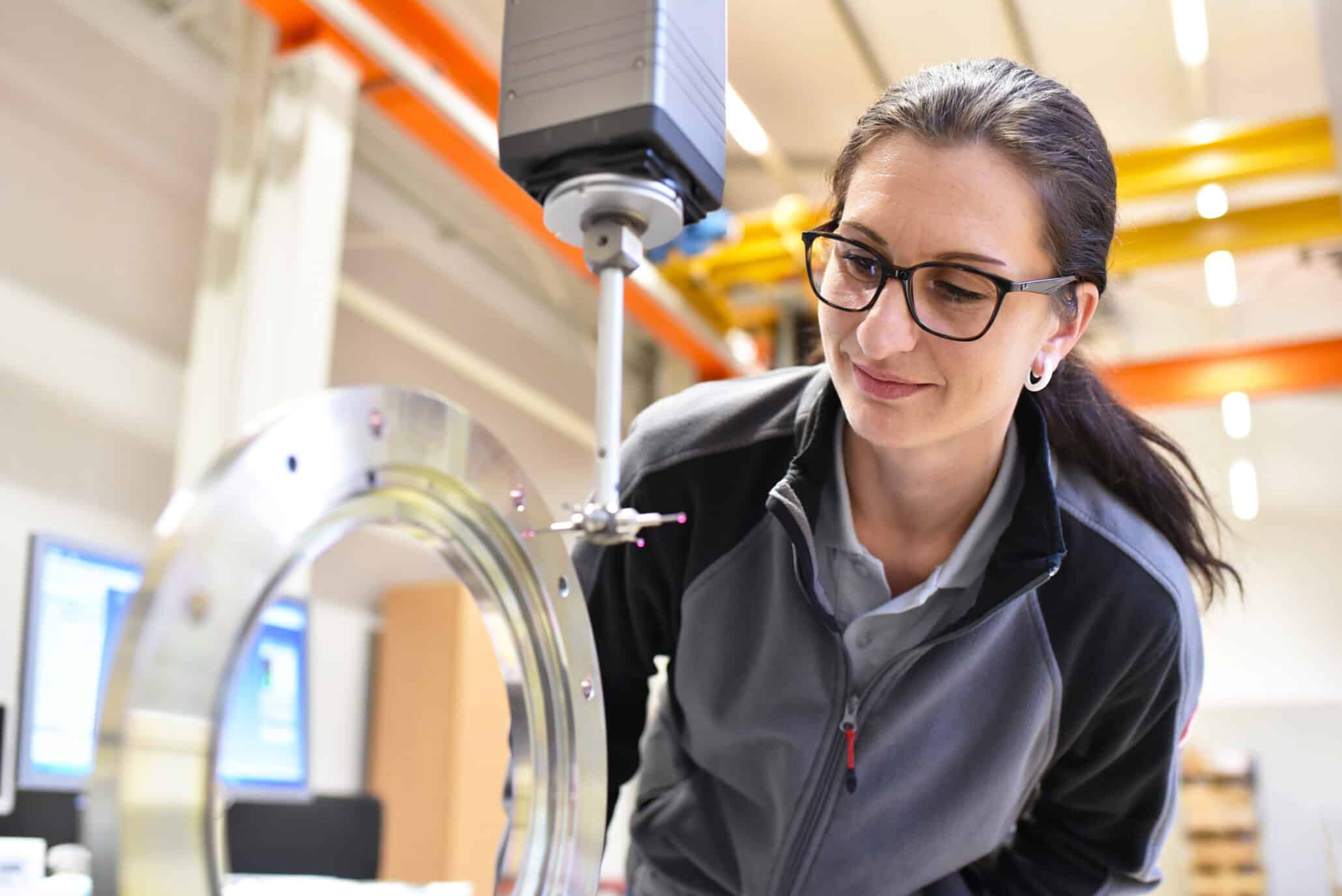 Frau als Maschinenbedienerin prüft den Ablauf in einer Industriehalle